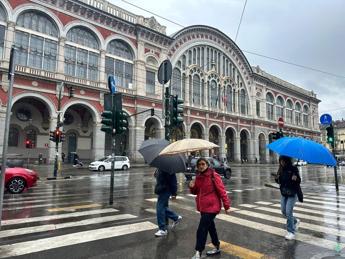 persone sotto la pioggia davanti a Porta Nuova